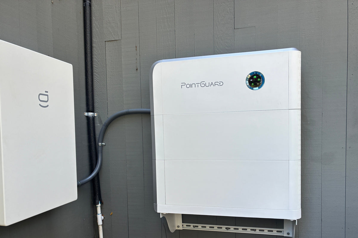 Two solar inverters mounted on a wall outdoors.
