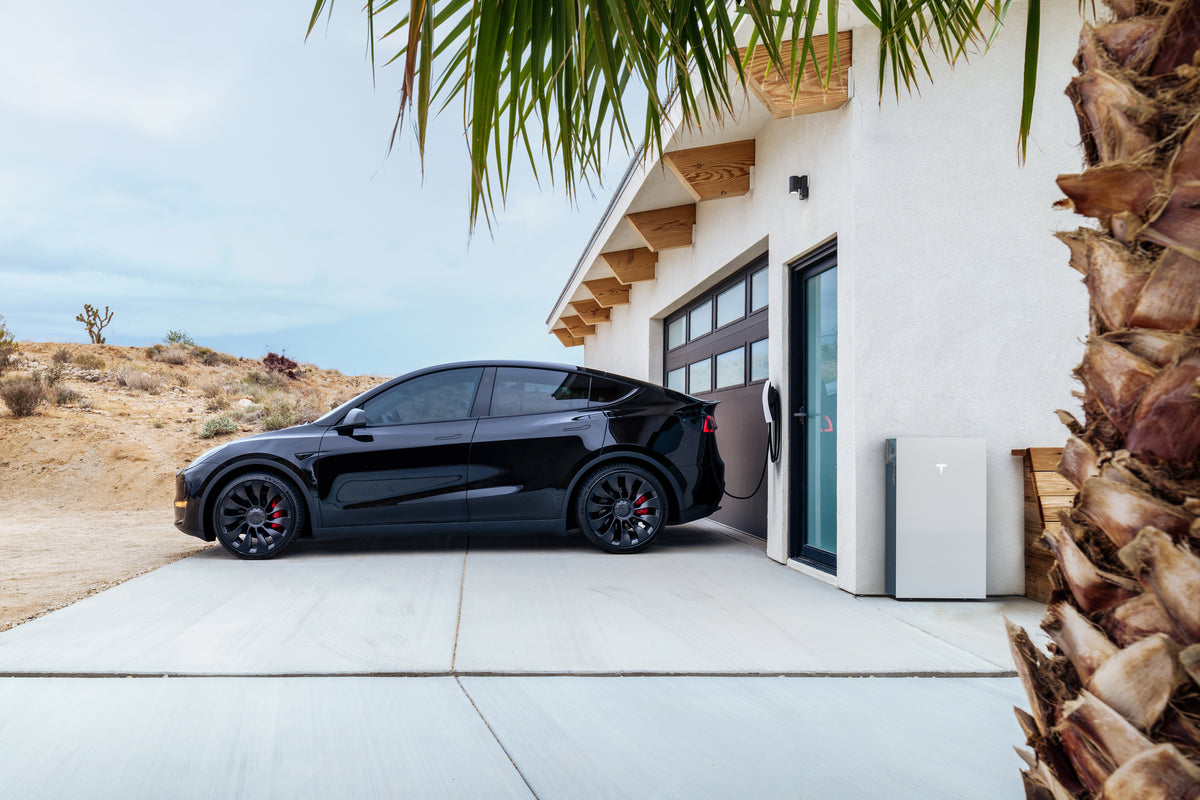Black electric car parked in a driveway with a modern house