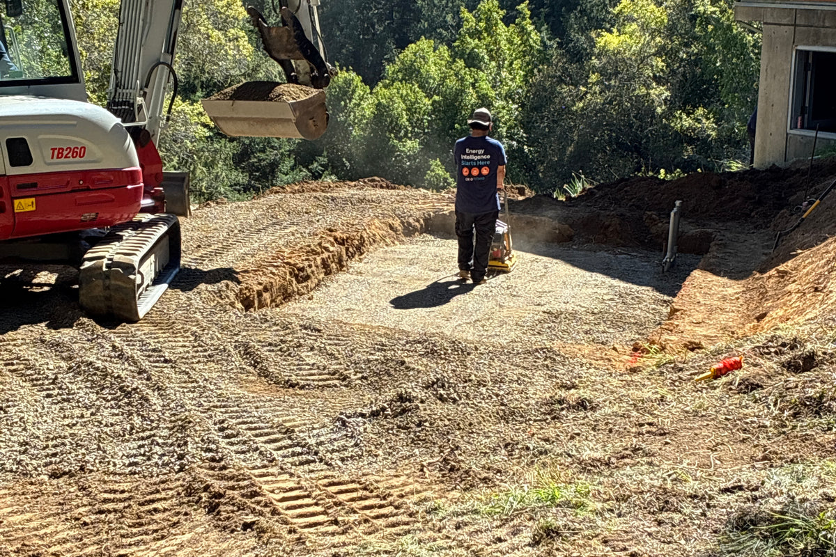 flattening a recently excavated hole outside a house in the forest
